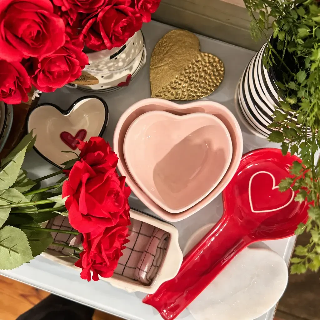 Pink and red heart-shaped dishes surrounded by flowers and carefully arranged gifts in the shop